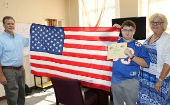 Principal, student and parent with flag
