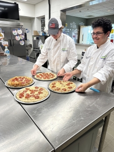 Two students making pizza.