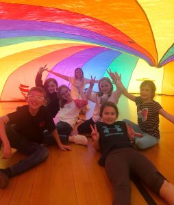 7 children under a rainbow tent