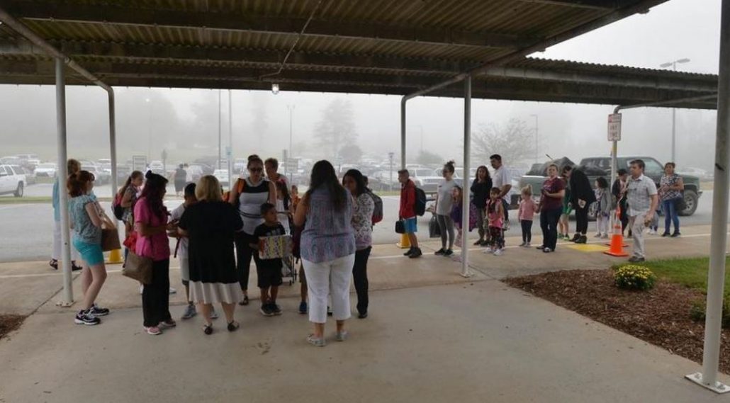 Students and adults gathered under awning
