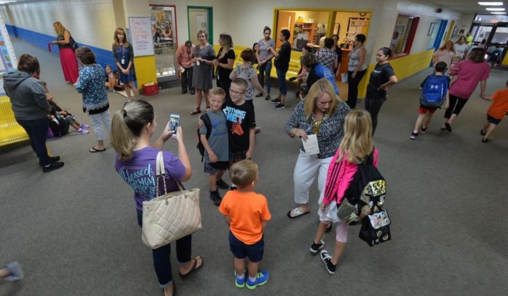Crowded hallways. AAn adult taking picture of two students.