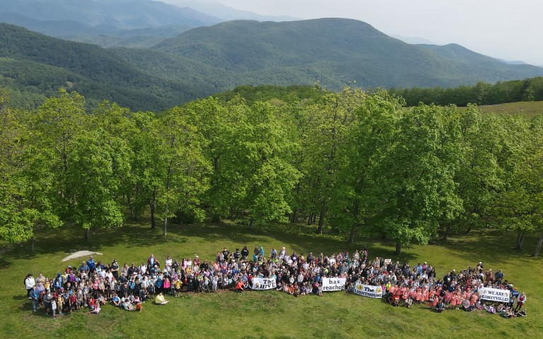 Classes gathered outside on lawn. Signs being held read The hive has reached the lighthouse we are Edneyville