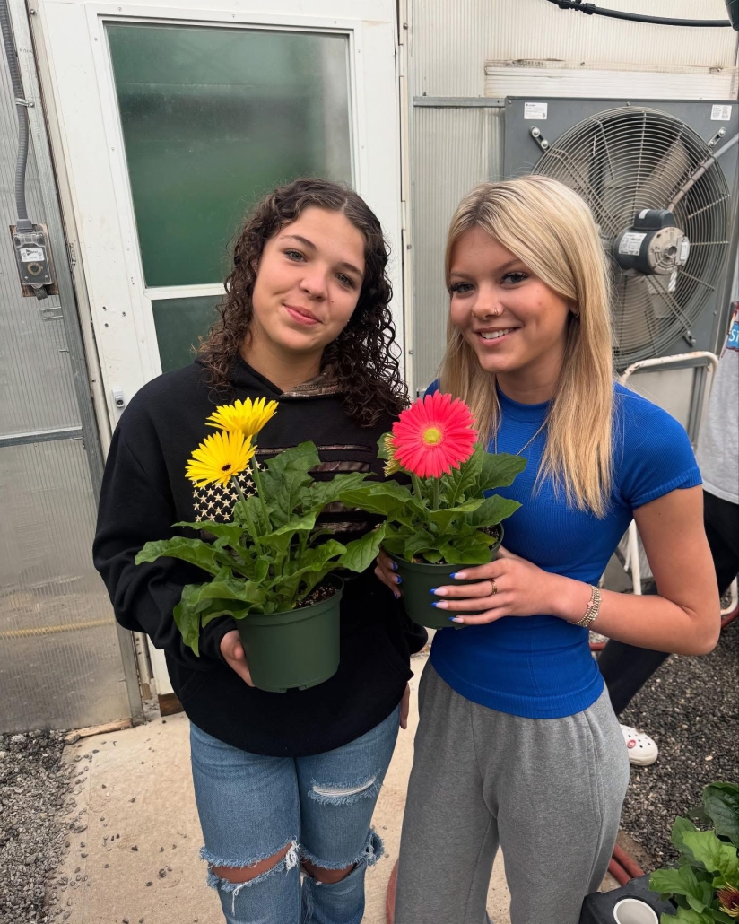 two girls holding daisies