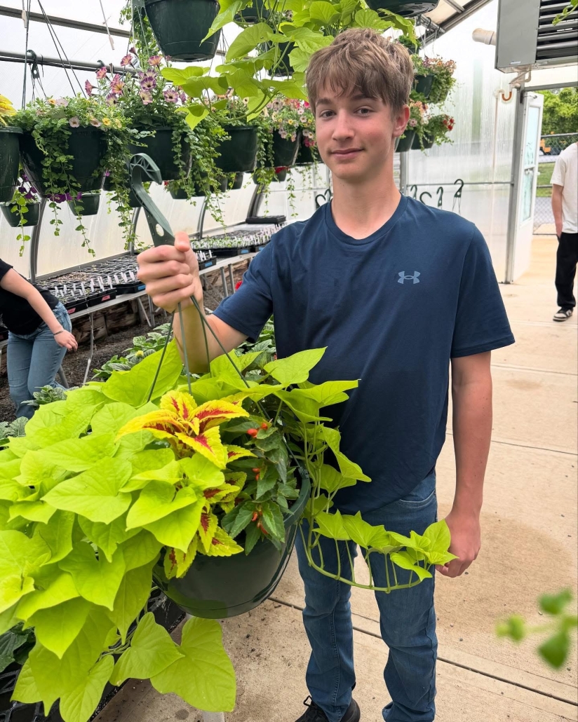 student holding hanging plant