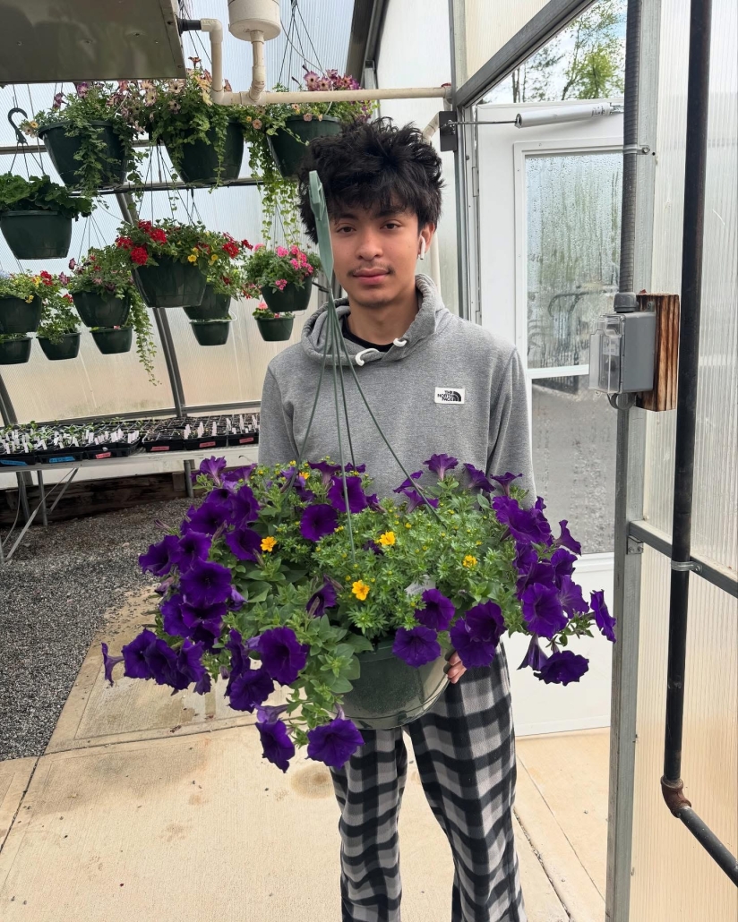 student holding purple hanging plant