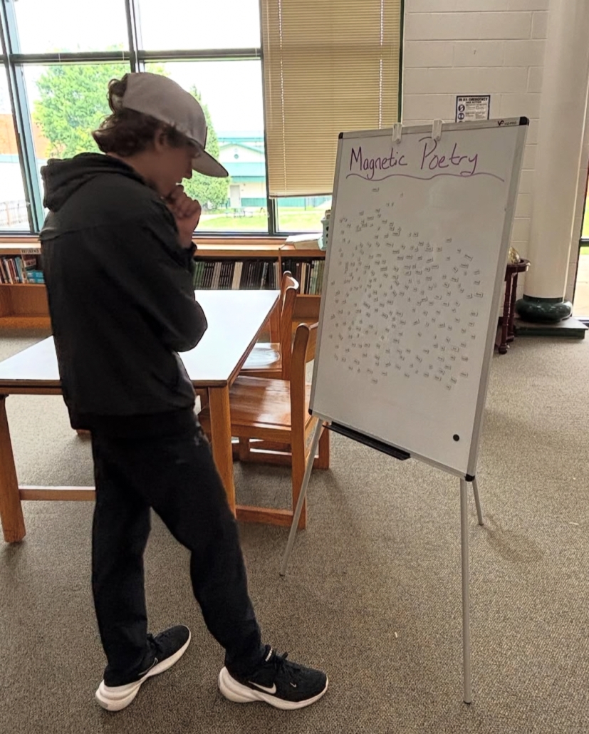 student thinking about magnetic poetry at easel