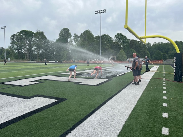 two students jumping onto water slide