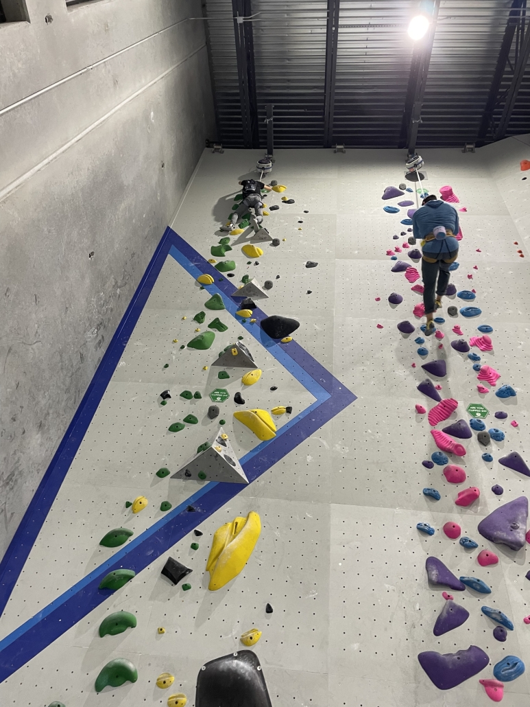 two students dual climbing on a rock wall