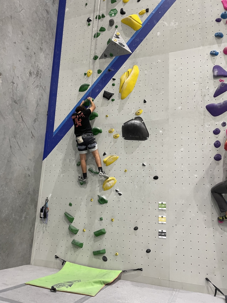 student rock climbing at indoor wall