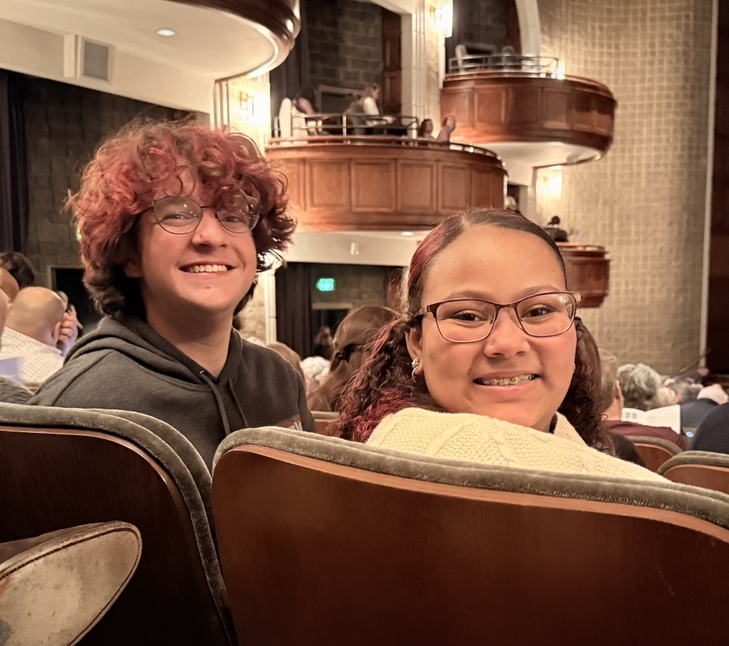 two students happily awaiting the show in their seats