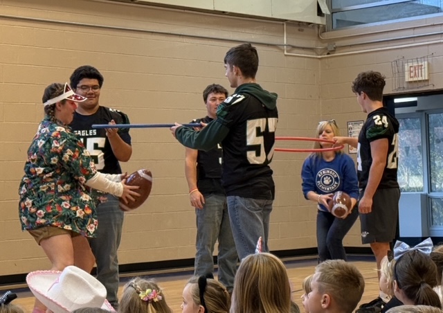 Football players playing a hula hoop game with two teachers