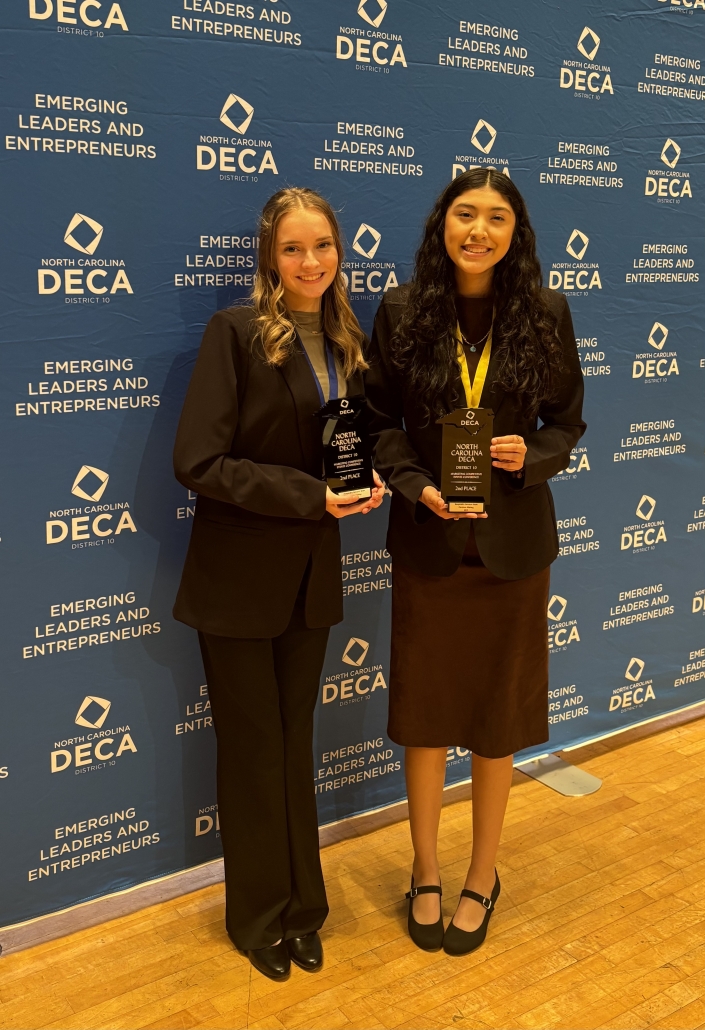 Sydney & Emily with medals on DECA backdrop