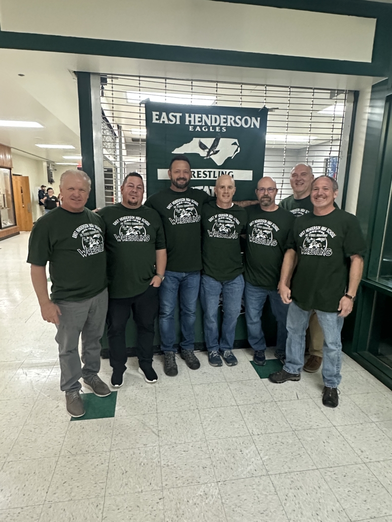 95-96 State Champ team and coaches in front of banner