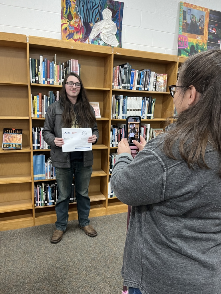 Mrs. Justice photographing Dallas with his certificate for the wall