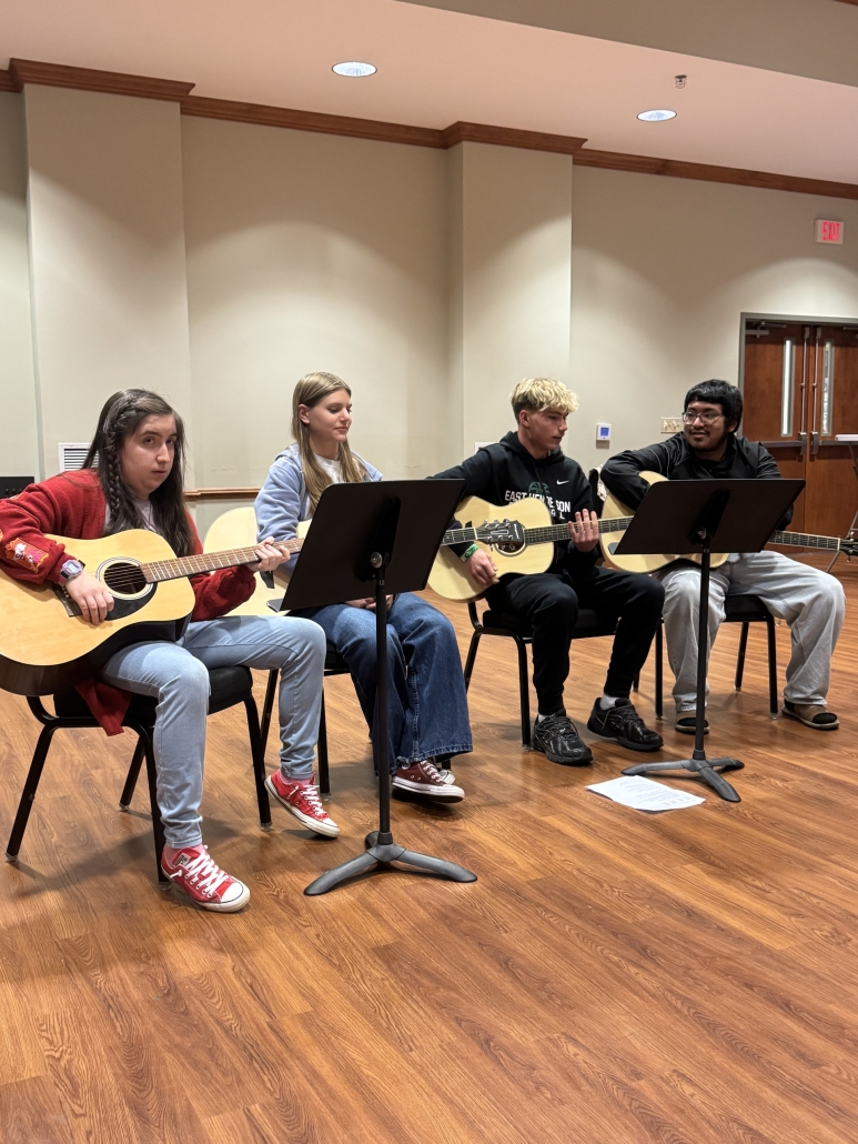 Four students playing guitar together