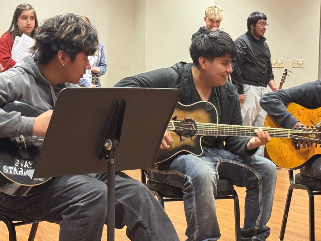 Two students playing guitar together