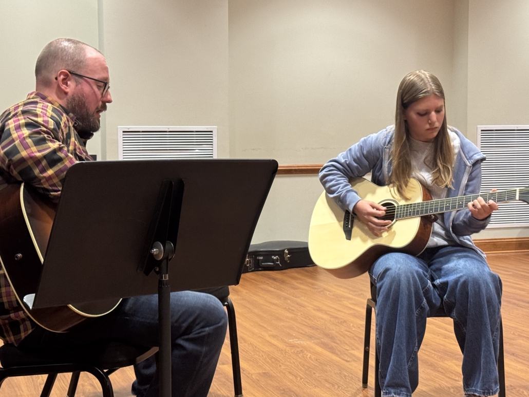 Student and teacher playing guitar together