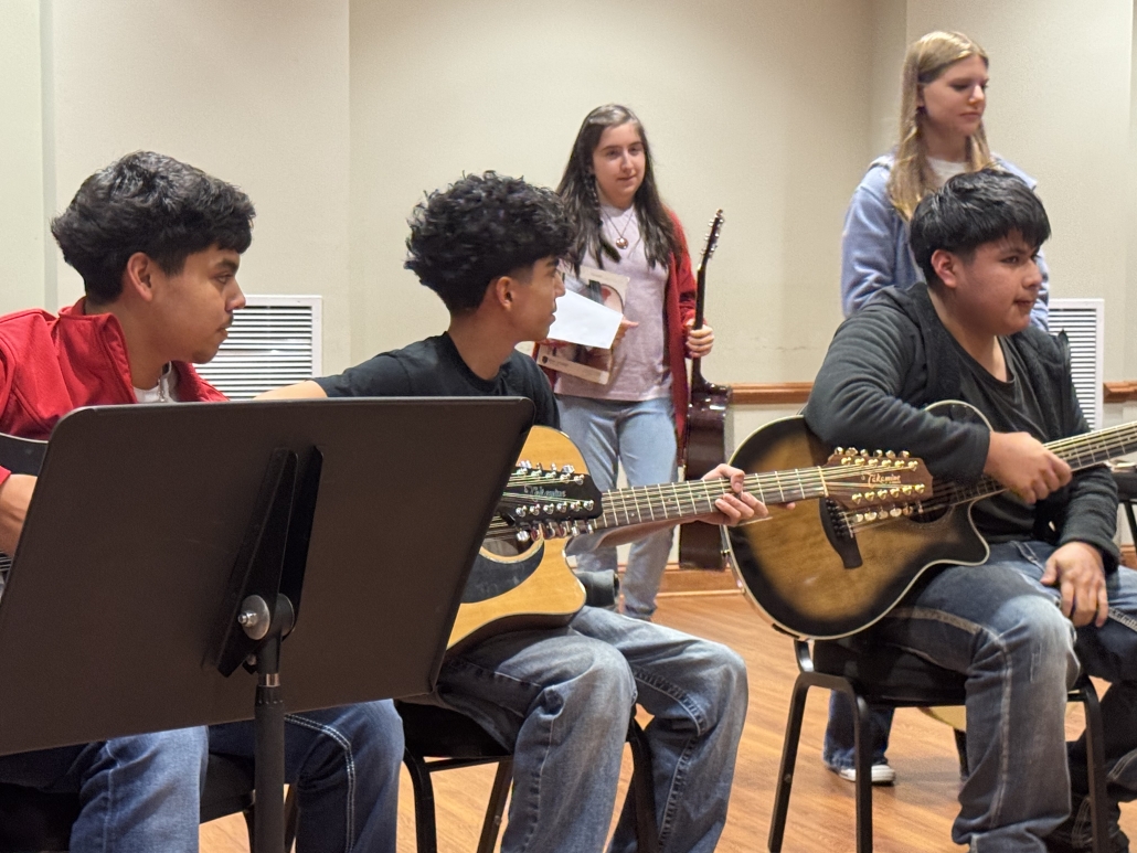 Three students playing guitar