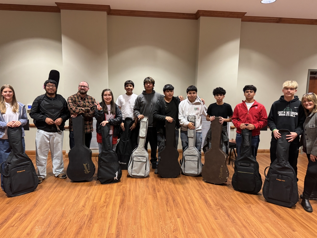 Group photo of Guitar Club with their guitars lined up in cases