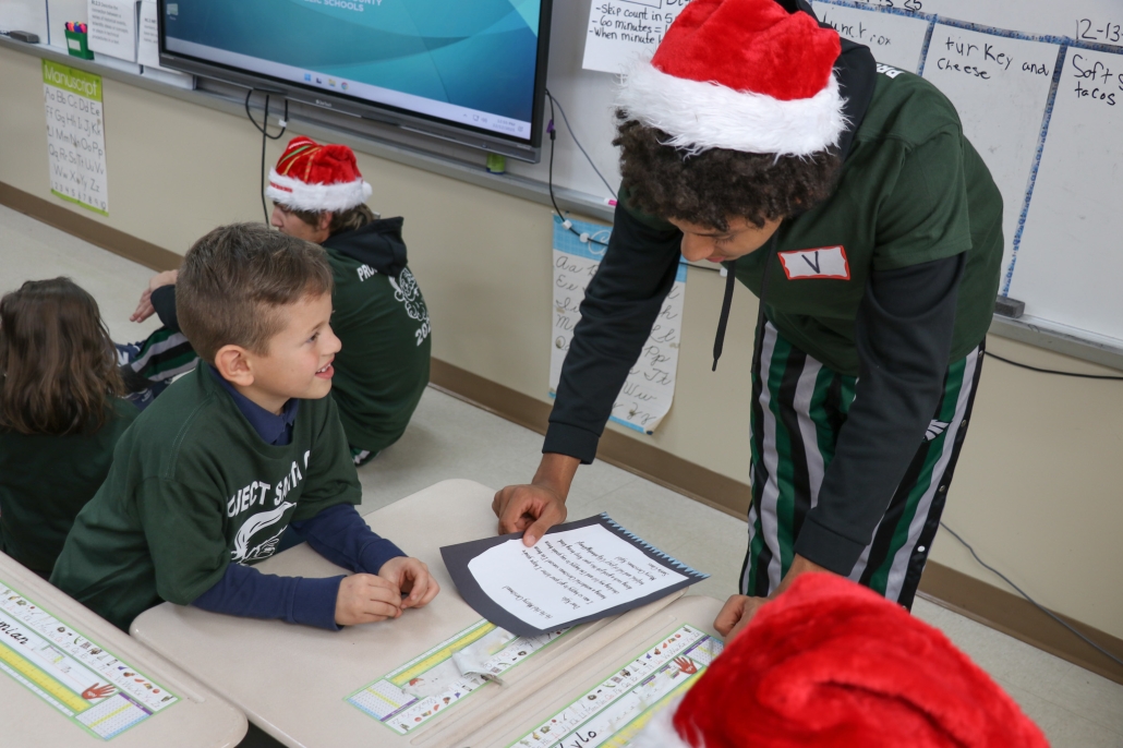 Jaylin reading to a little boy smiling