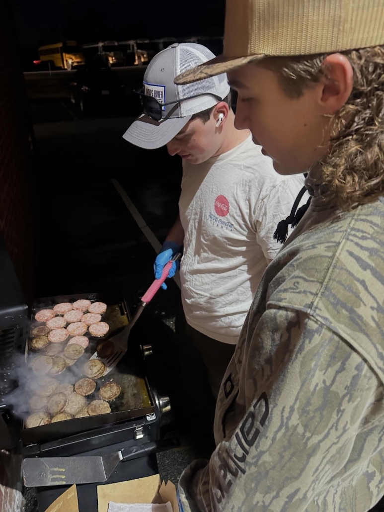 Two boys cooking sausages on out on the grill