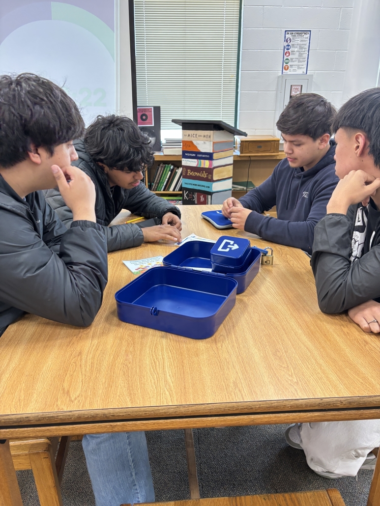 Four boys working on a lock box for a poetry Breakout