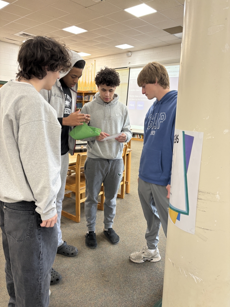4 boys standing solving a clue for the poetry Breakout