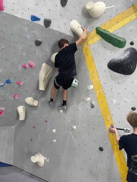 Student climbing on corner of rock wall