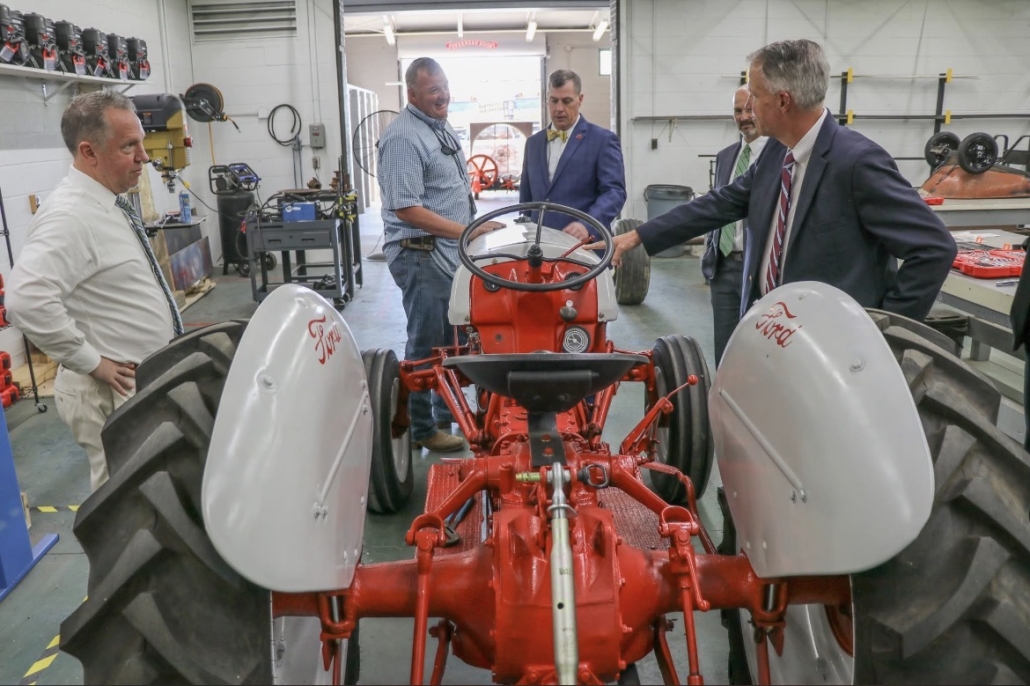 Mr. Scott, Mr. Rollins, Mr. Garrett, Dr. Taylor, and Mr. Rhodes around a tractor