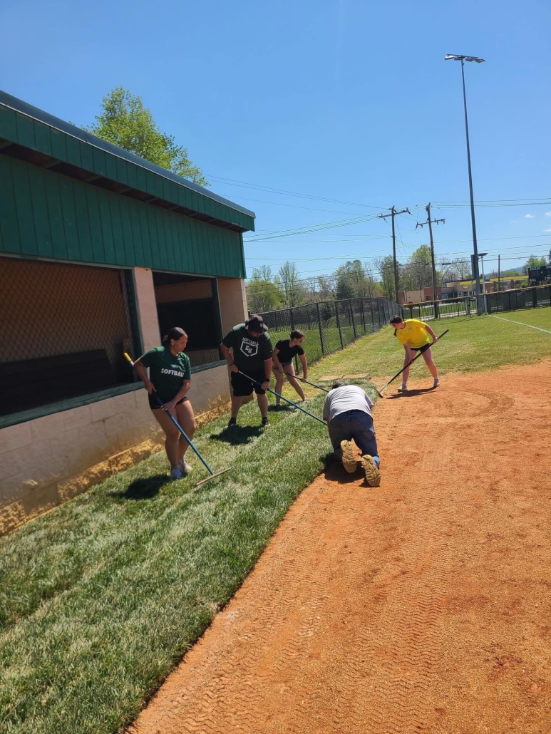 players and coach laying sod