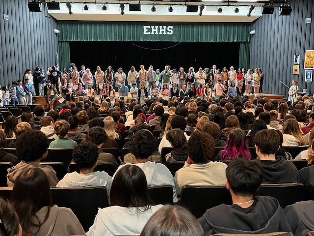 8th graders seated and listening to Mr. Scott in auditorium