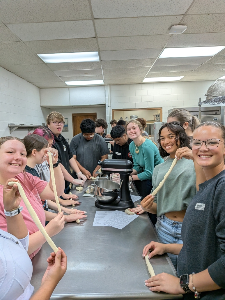 Chemistry students stretching dough at culinary table