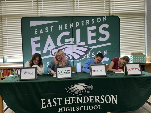 4 arts students signing at the table