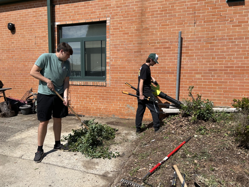 Two students piling up brush and weeds