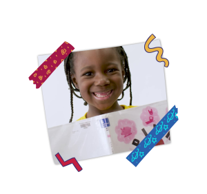 A student smiling at the camera with a book. 