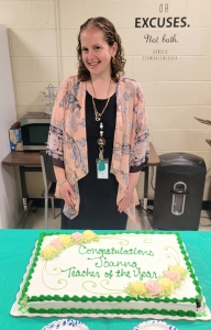 Joanna Leslie stands behind a cake that reads Congratulations Joanna Teacher of the Year