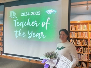 Heather Knapp standing in front of a sign that says 2024-2025 Teacher of the Year