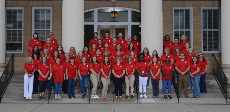 Photo of HMS faculty and staff standing on steps of the historic county courthouse, smiling.