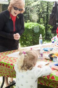 A woman smiles as a child does a craft.