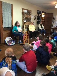 Three women in front of a class of children.