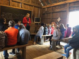 Students sit in the replica one-room schoolhouse.