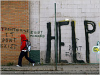 HELP Graffiti on wall. Youth in red hoodie walking past the wall.