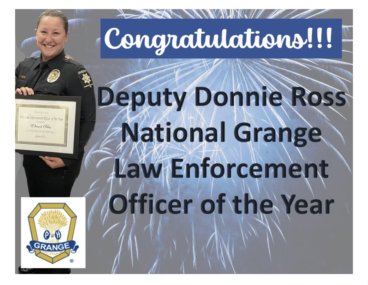 Fireworks on gray background with sheriff deputy woman in black uniform holding a framed certificate. Congratulations!!! Deputy Donnie Ross National Grange Law Enforcement Officer of the Year. Grange symbol.