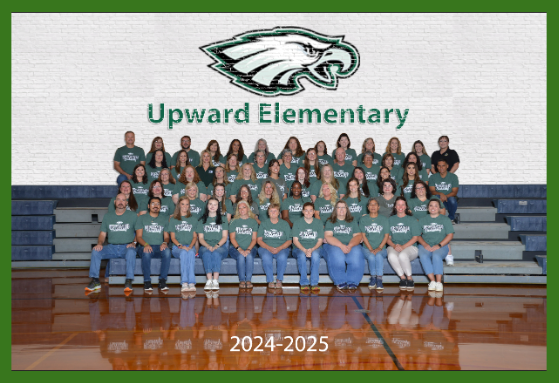 The members of Upward Elementary's staff are sitting on the bleachers wearing jeans and an Upward t-shirt.