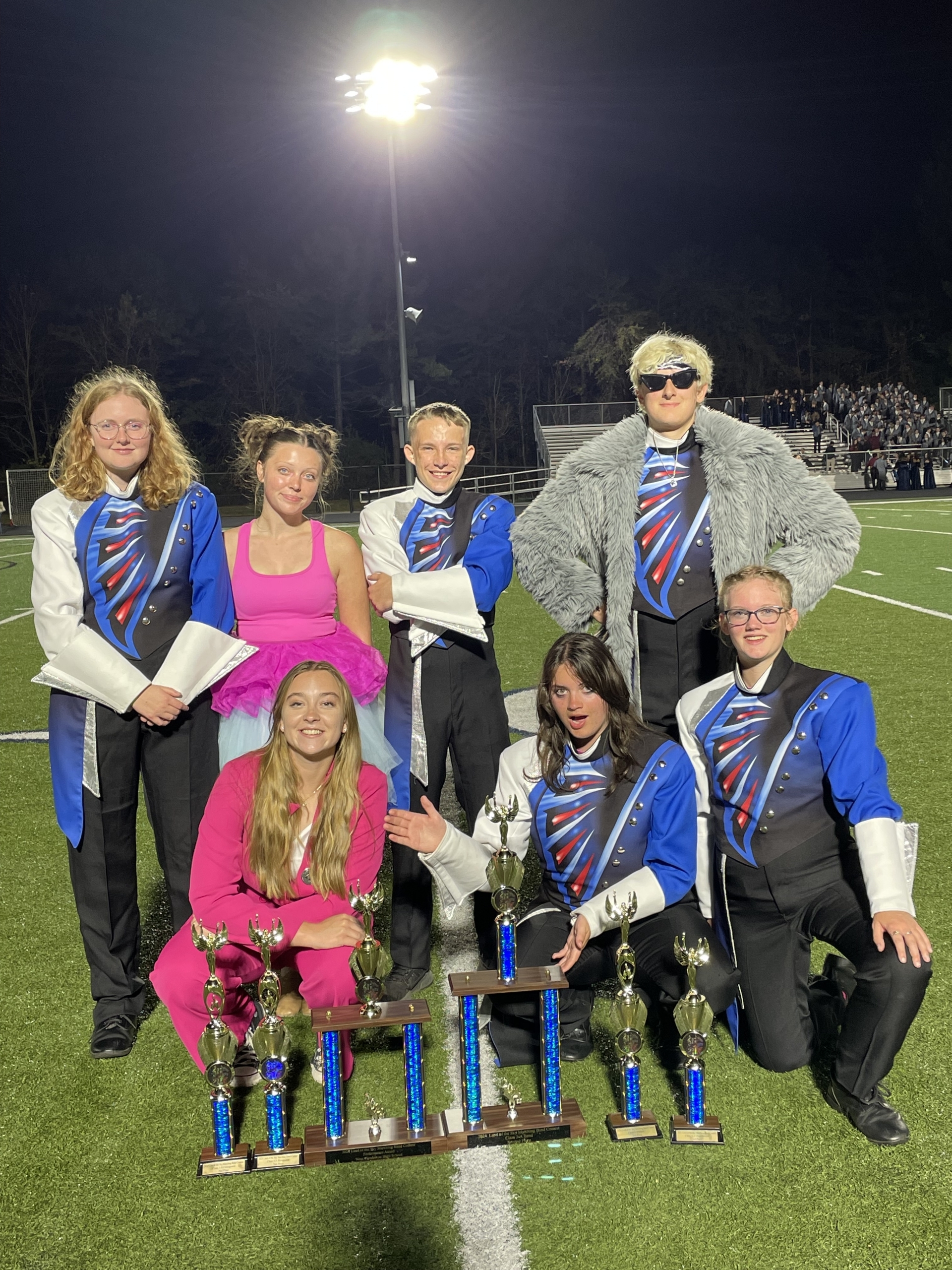 Seniors representing the West Henderson Marching Band display awards earned at a recent band contest. They are wearing marching band uniforms and costumes from their recent halftime show.