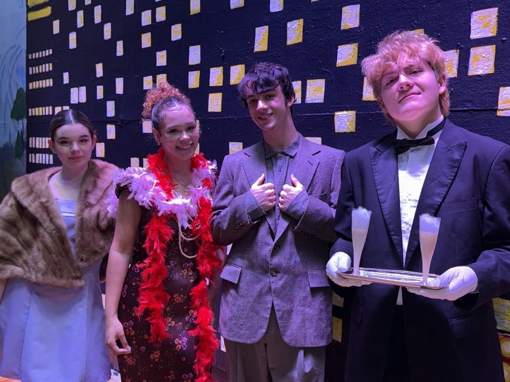 Students who a part of Annie Jr. posing in front of the background.