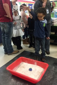 student dropping ball into sand