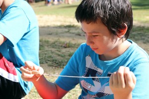 Student stringing button on string