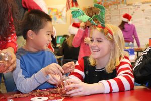 High school student helps 1st-grader make ornament