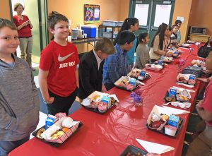 Students standing at lunch table.